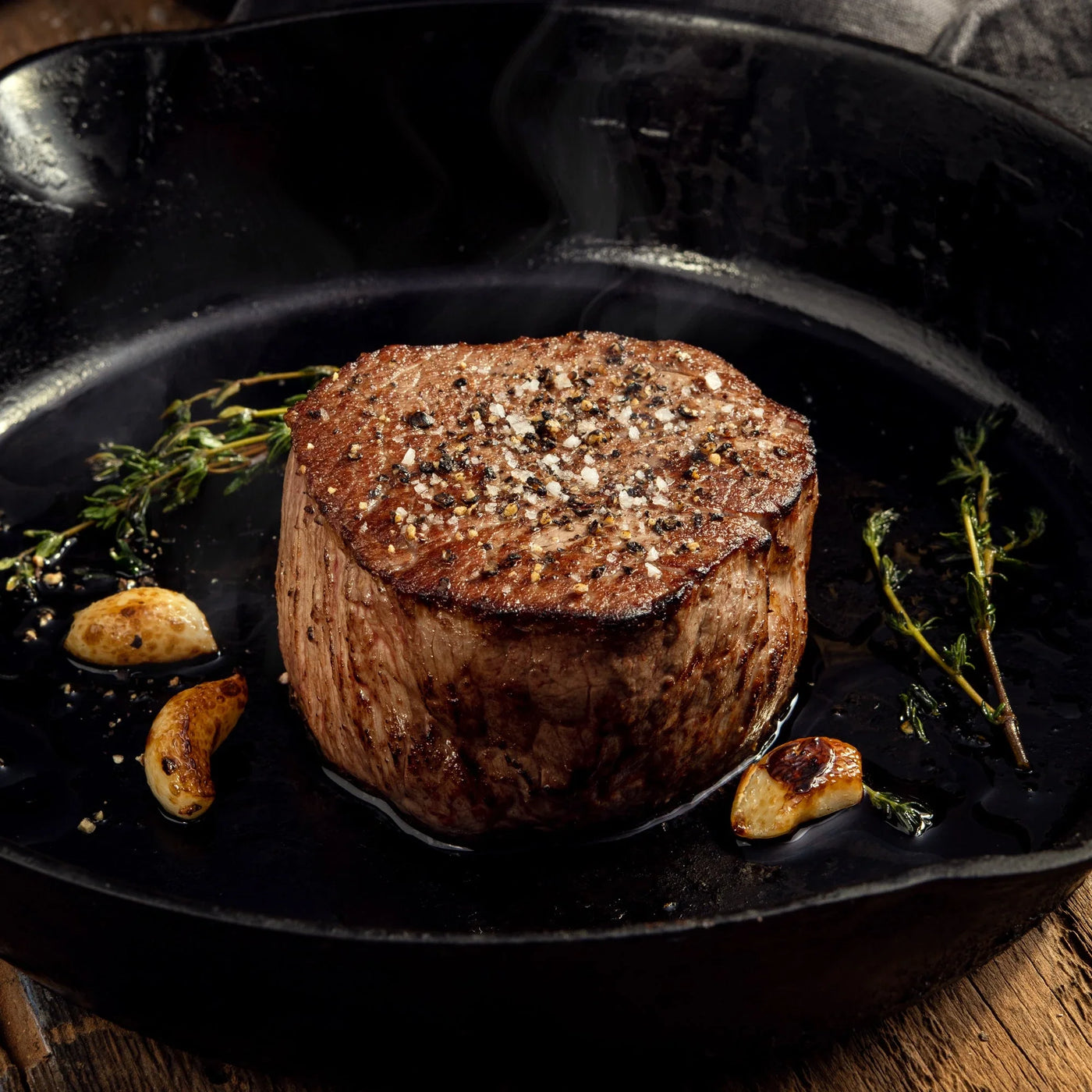 cooked Filet Mignon steak on skillet with seasoning 